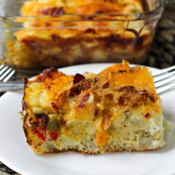 cheesy egg obrien casserole on a white plate with a fork.