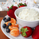 strawberries, oranges and blueberries next to fruit dip.