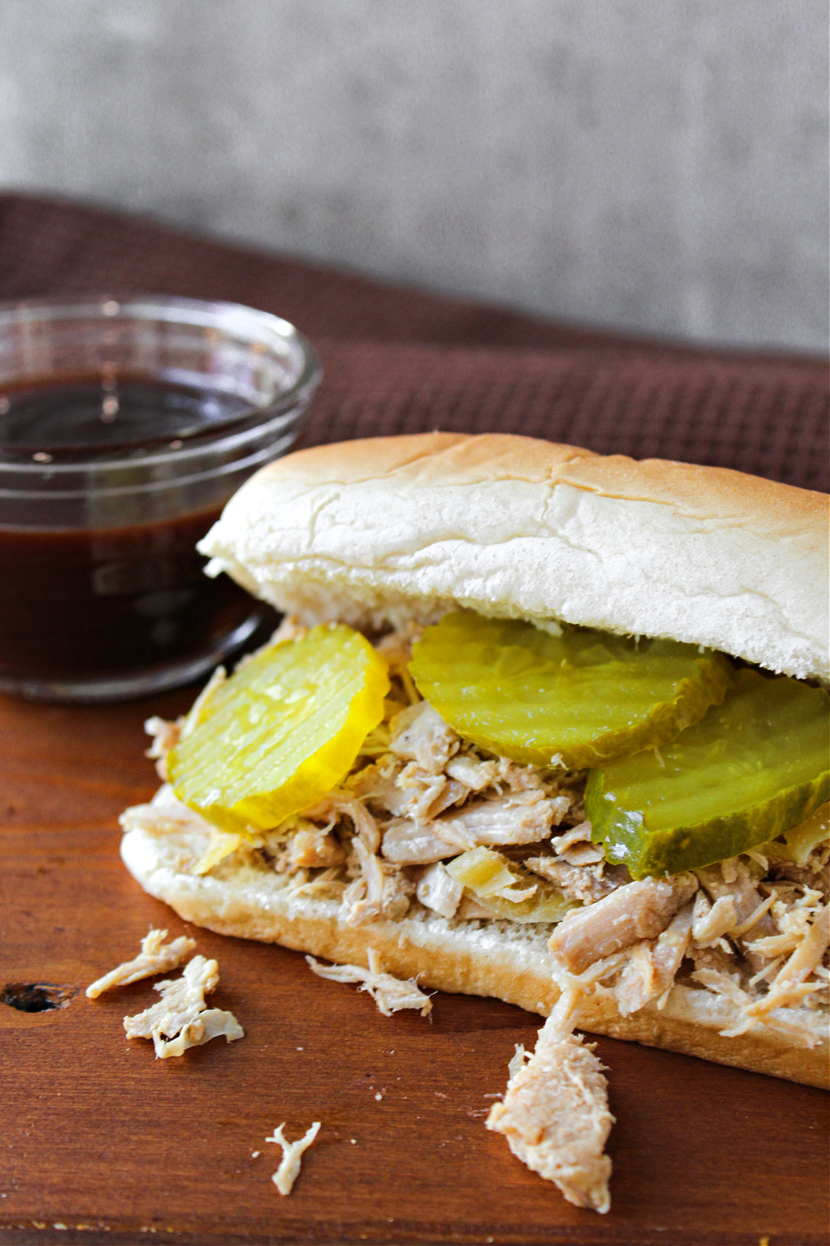 slow cooker pulled pork on a brown cutting board.