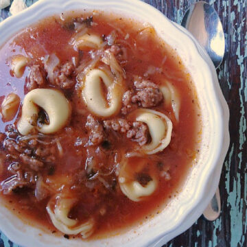 Sausage tortellini soup in a white bowl
