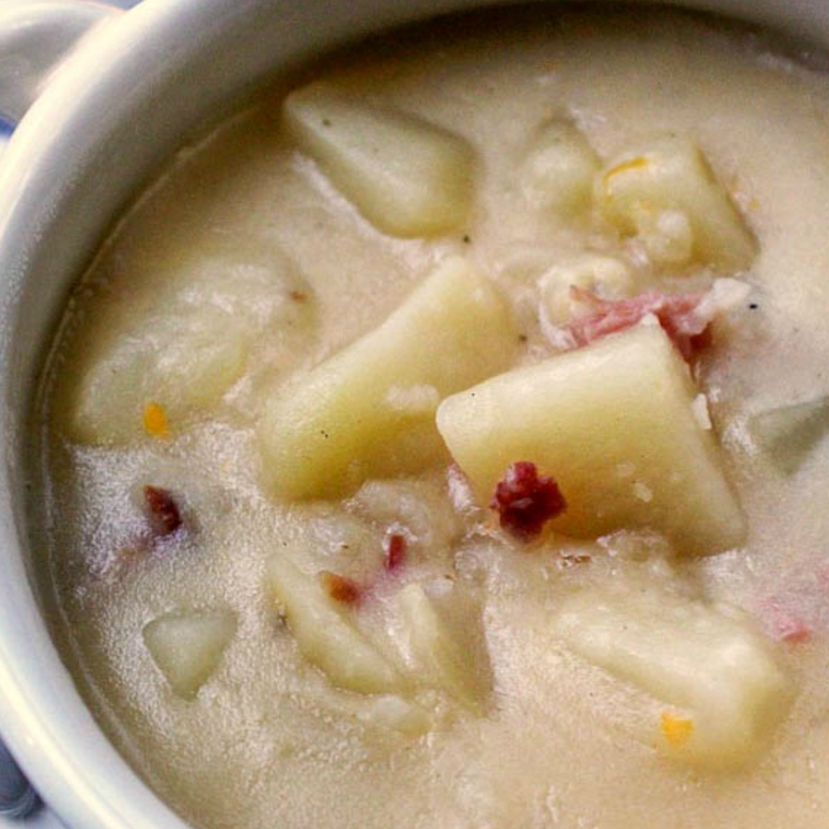 creamy potato soup in a white bowl with bacon bits