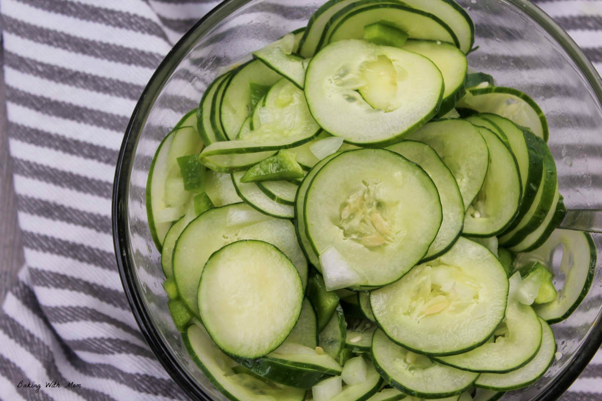 Chopped cucumbers in a clear bowl on a striped towel