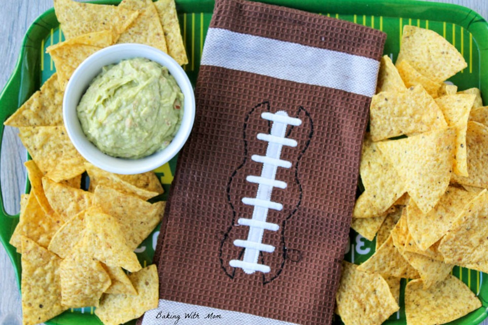 Football towel and easy homemade guacamole dip with chips on a tray