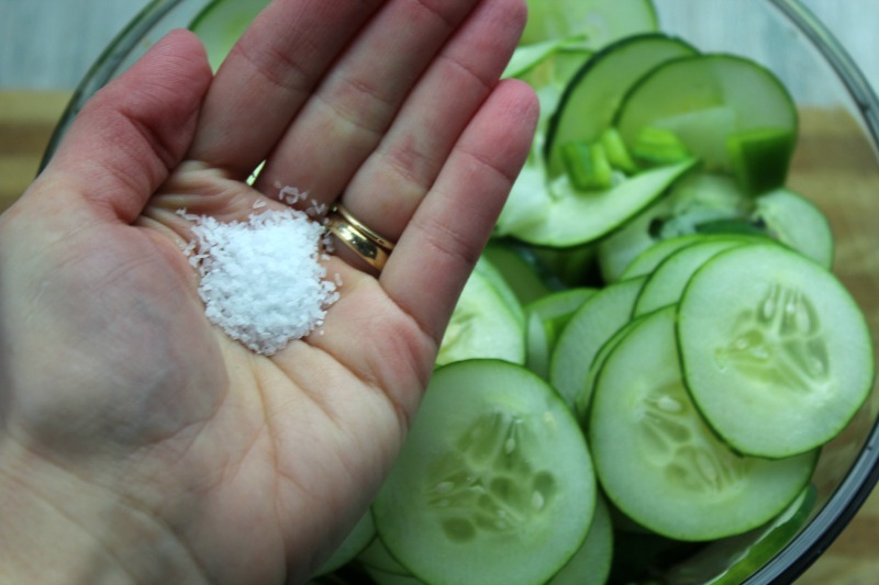 Coarse salt in a hand over cucumbers