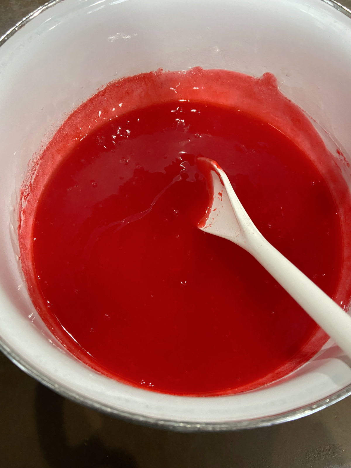 strawberry gelatin in a white pan with a spoon. 