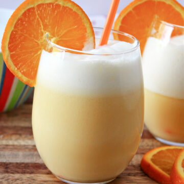 orange Julius in a clear glass with a straw and orange slice.
