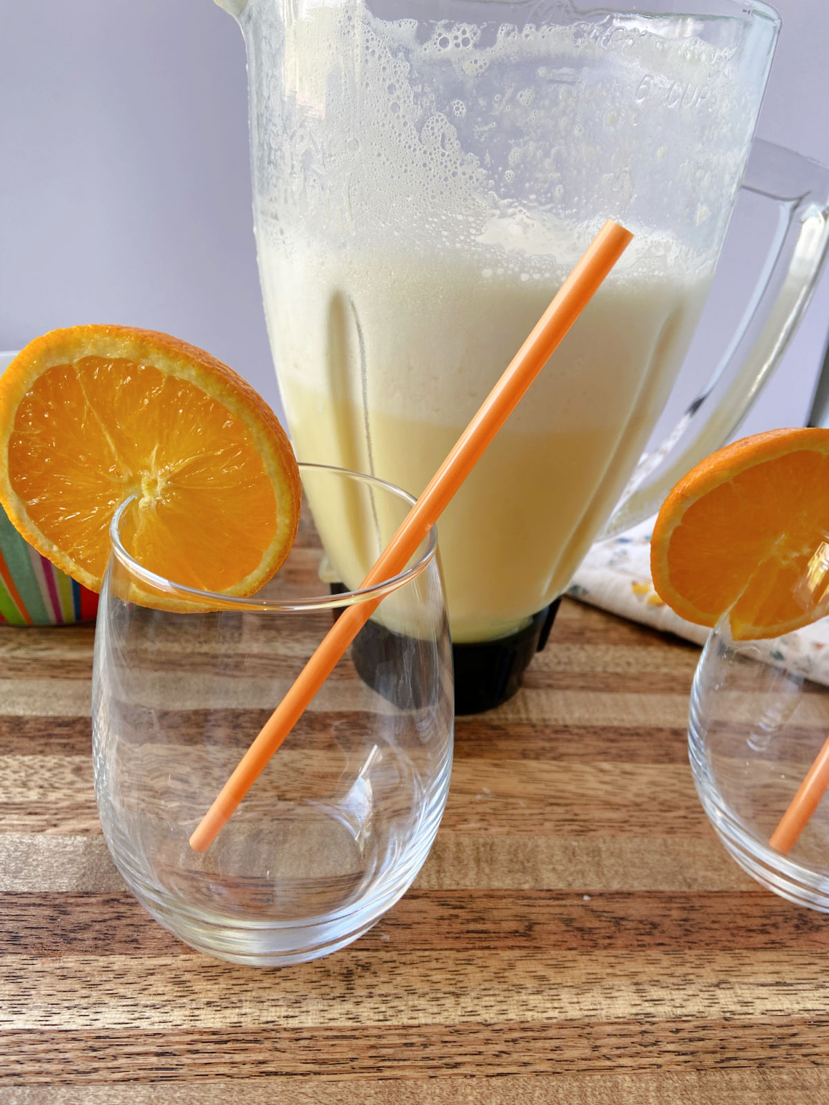 orange julius in a blender with clear glasses besides. 