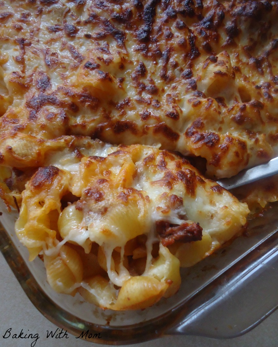 A spoon scooping up casserole with layers of cheese and noodles