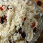 close up of rice, apples and craisins in a clear dish