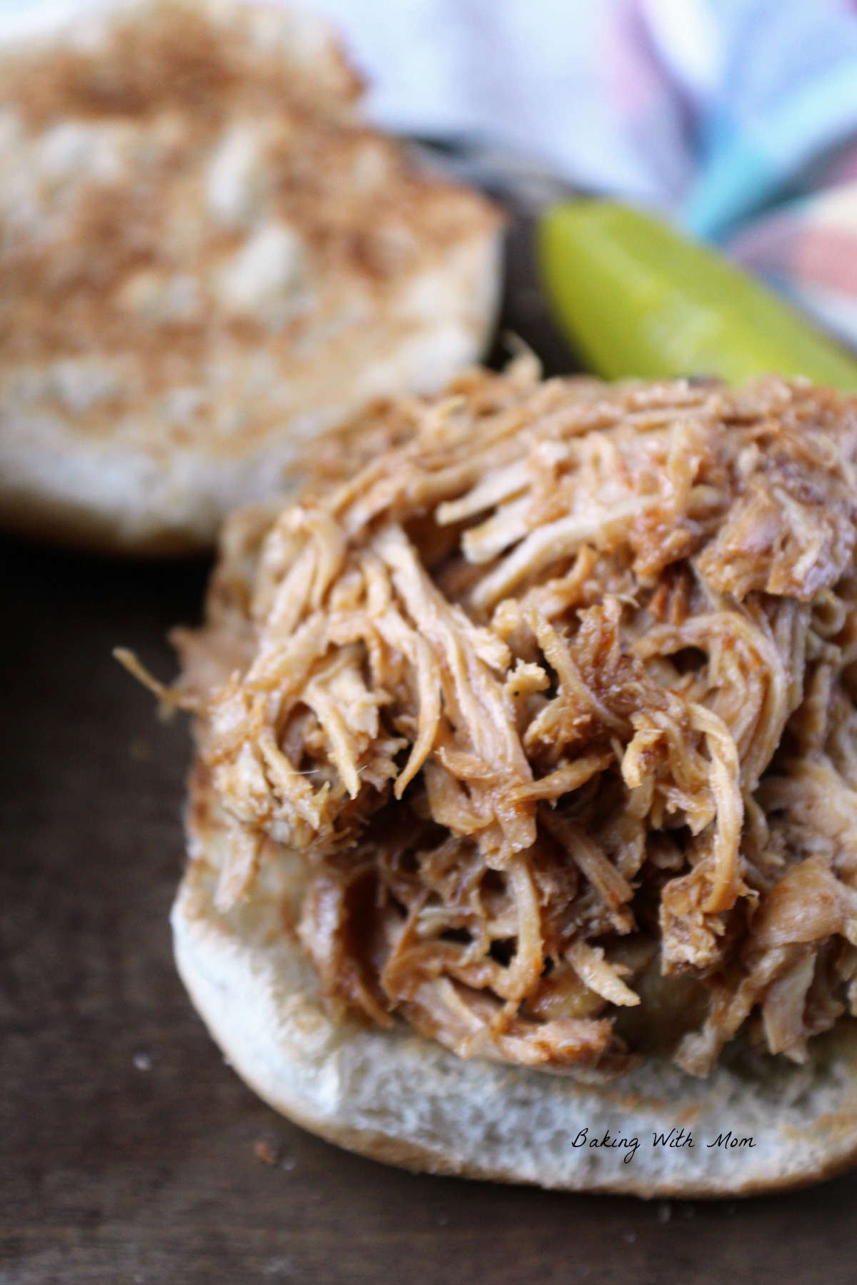 Shredded chicken on a hamburger bun with BBQ sauce. 