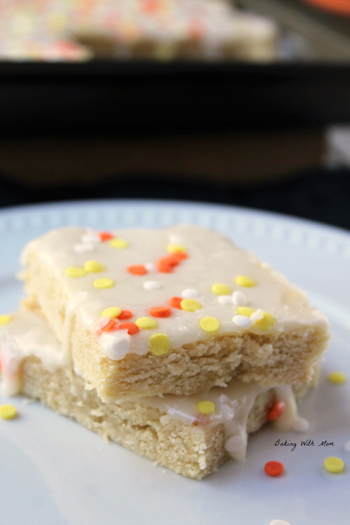 Two sugar cookie stacked on a plate with fall colored sprinkles on top