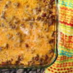 enchilada casserole in a clear casserole dish with beans, hamburger and cheese