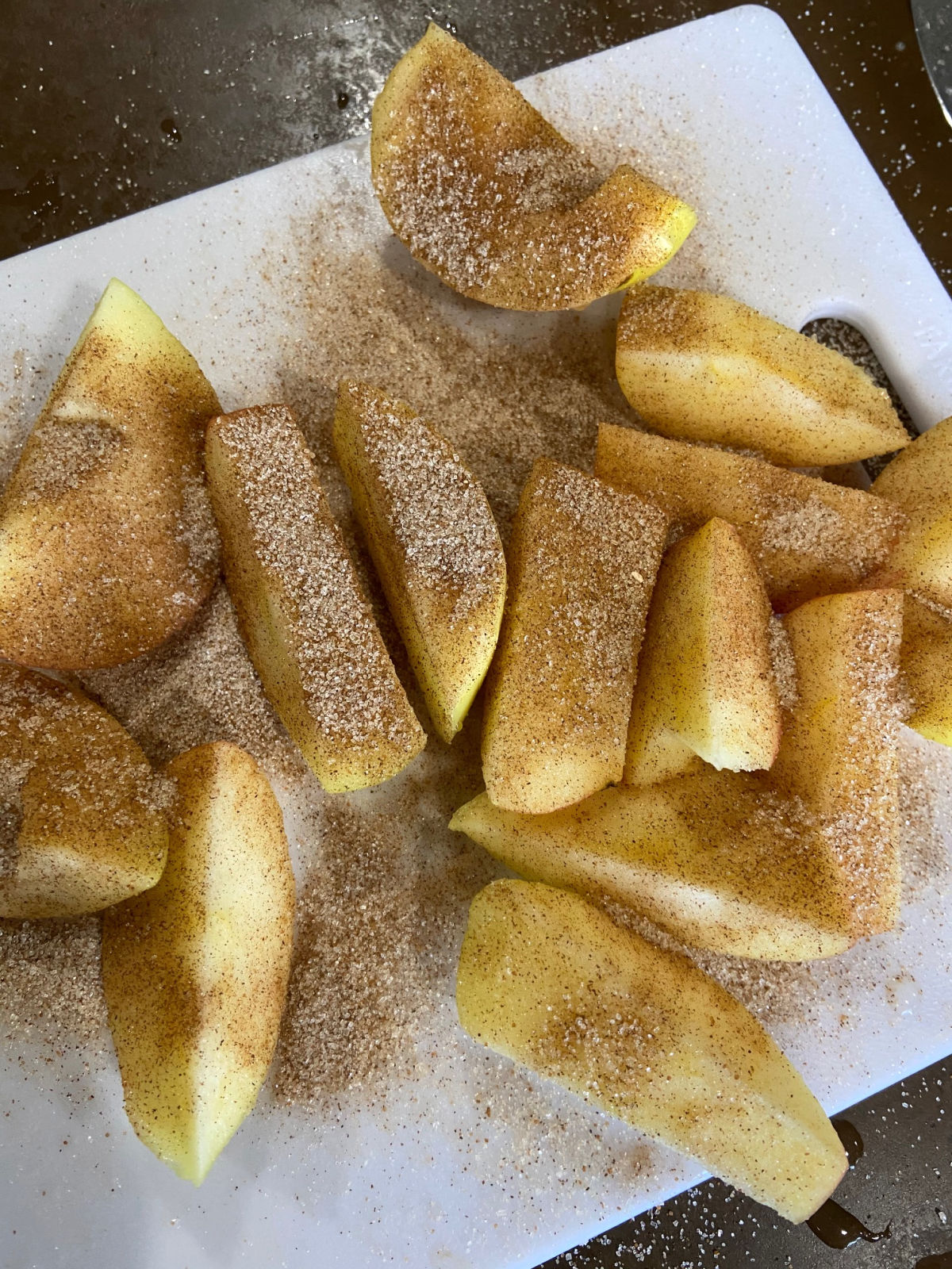 Apples on a cutting board covered in cinnamon sugar