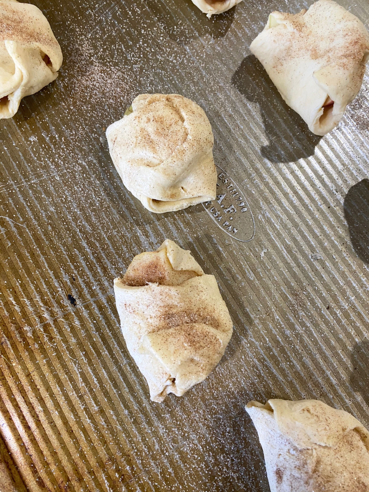 Crescent rolls with apple slices inside on a baking sheet