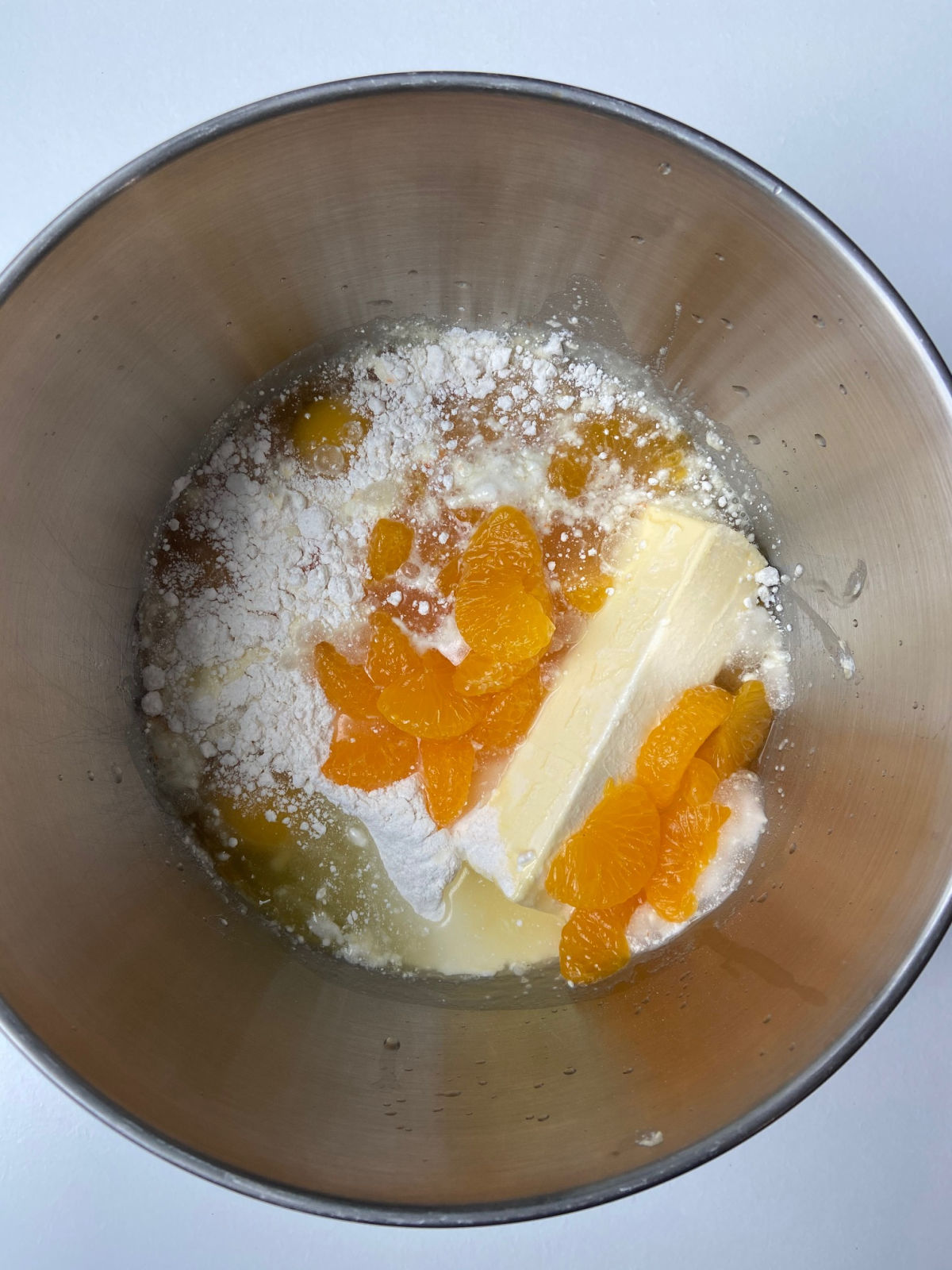 Mixing bowl with butter, mandarin oranges, cake mix inside