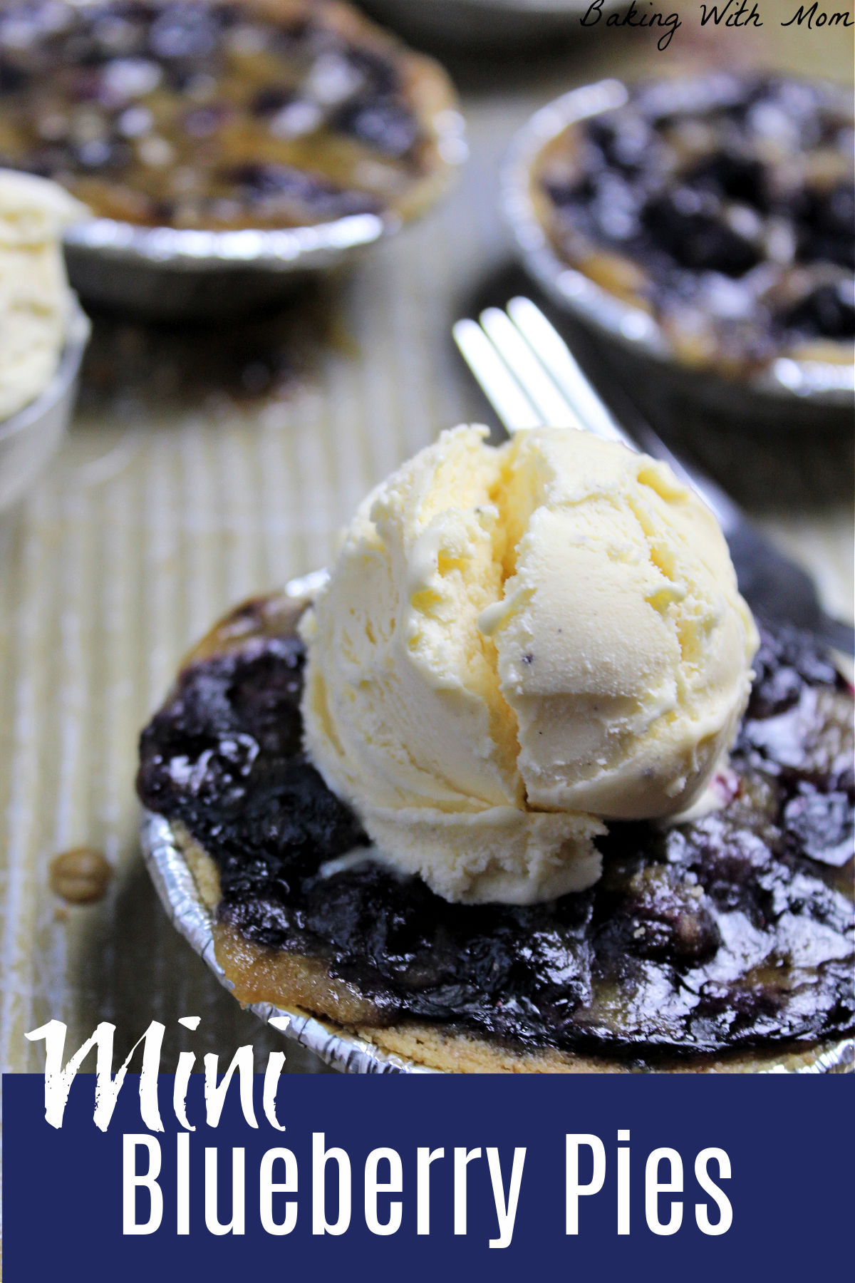 Blueberry pies on a baking sheet with a scoop of ice cream on top.
