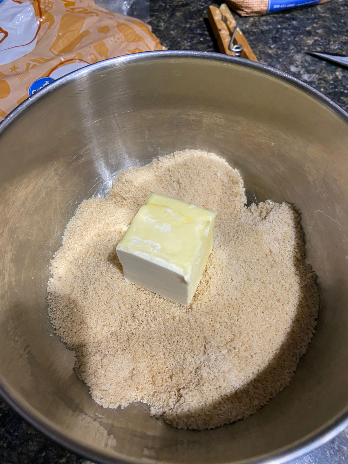 Brown sugar and flour mixed together in a silver bowl with butter on top. 