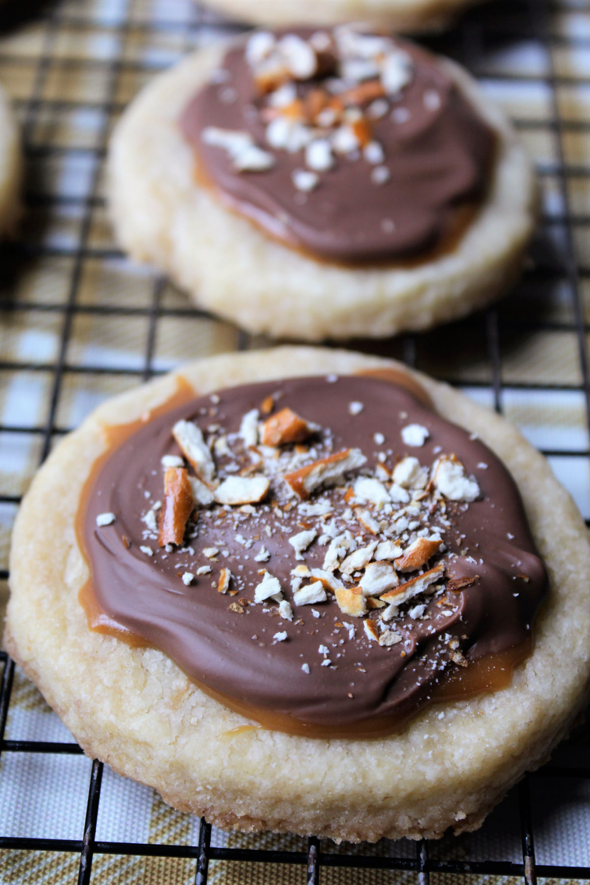 caramel shortbread cookie with pretzels on top of a cooling rack