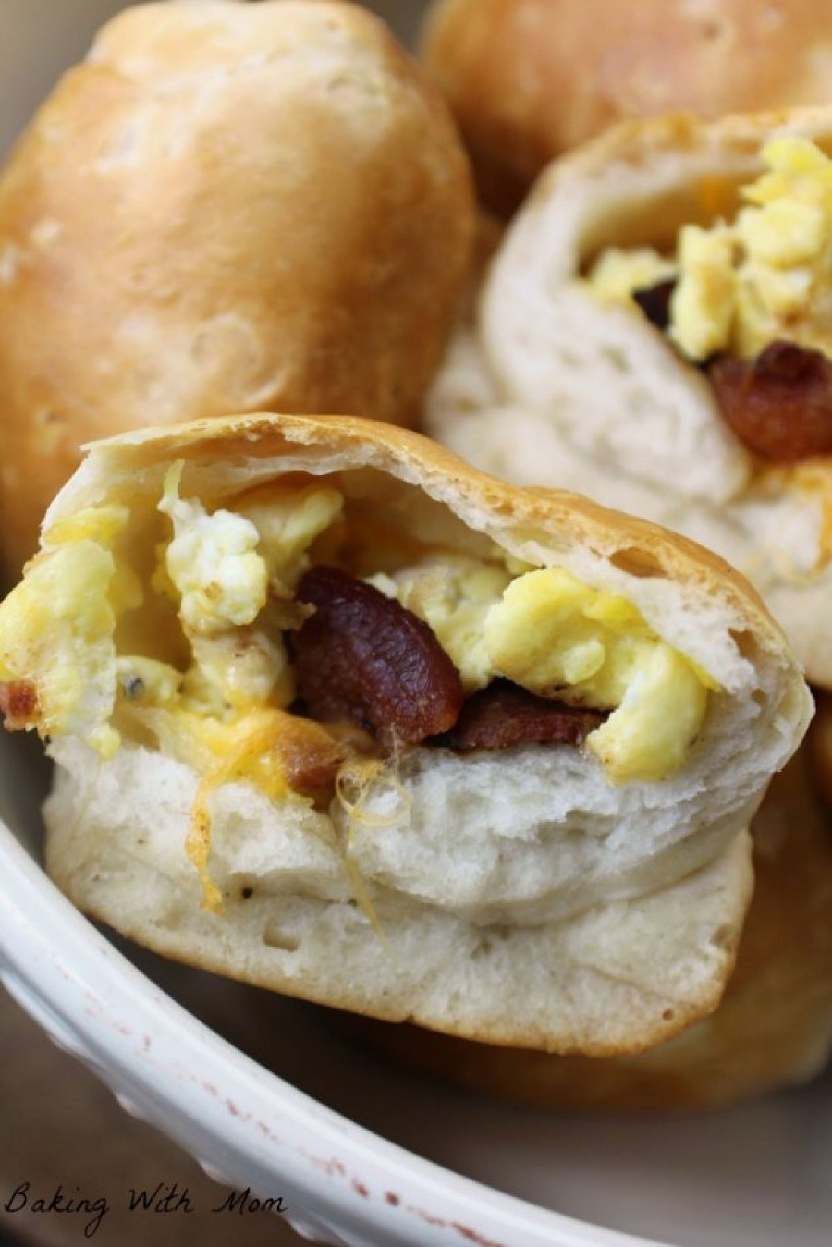 Biscuits stuffed with eggs, bacon, cheese in a cream colored bowl. 