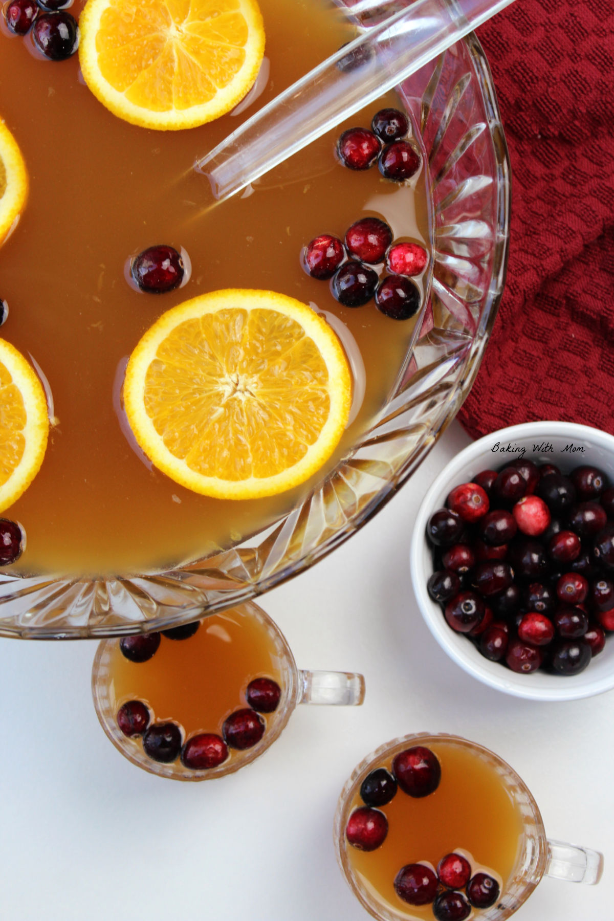 Bowl of punch with cranberries and orange slices floating on top.