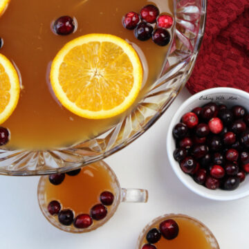 Christmas punch in a clear punch bowl with orange slices and cranberries on top