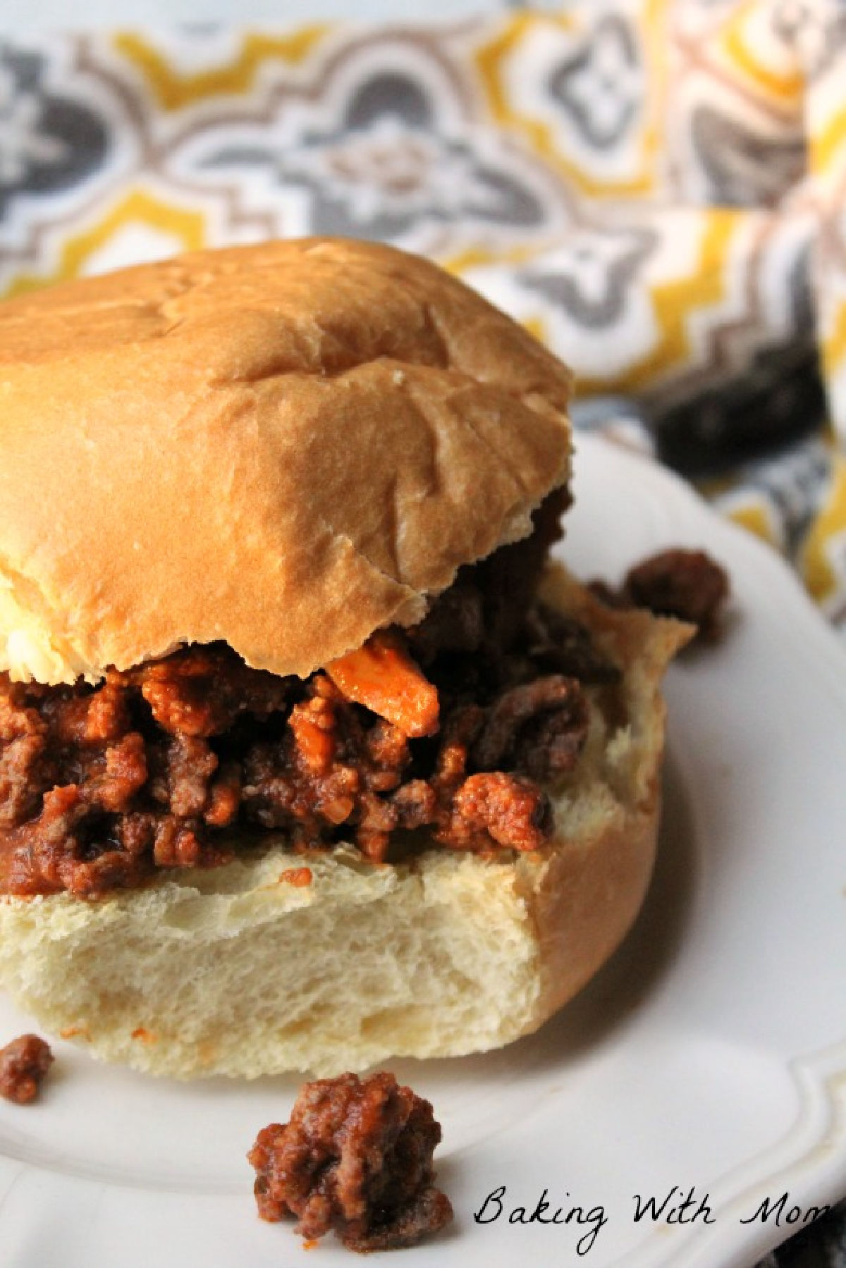 Burger on a hamburger bun with pepperoni and mushrooms on a white plate. 