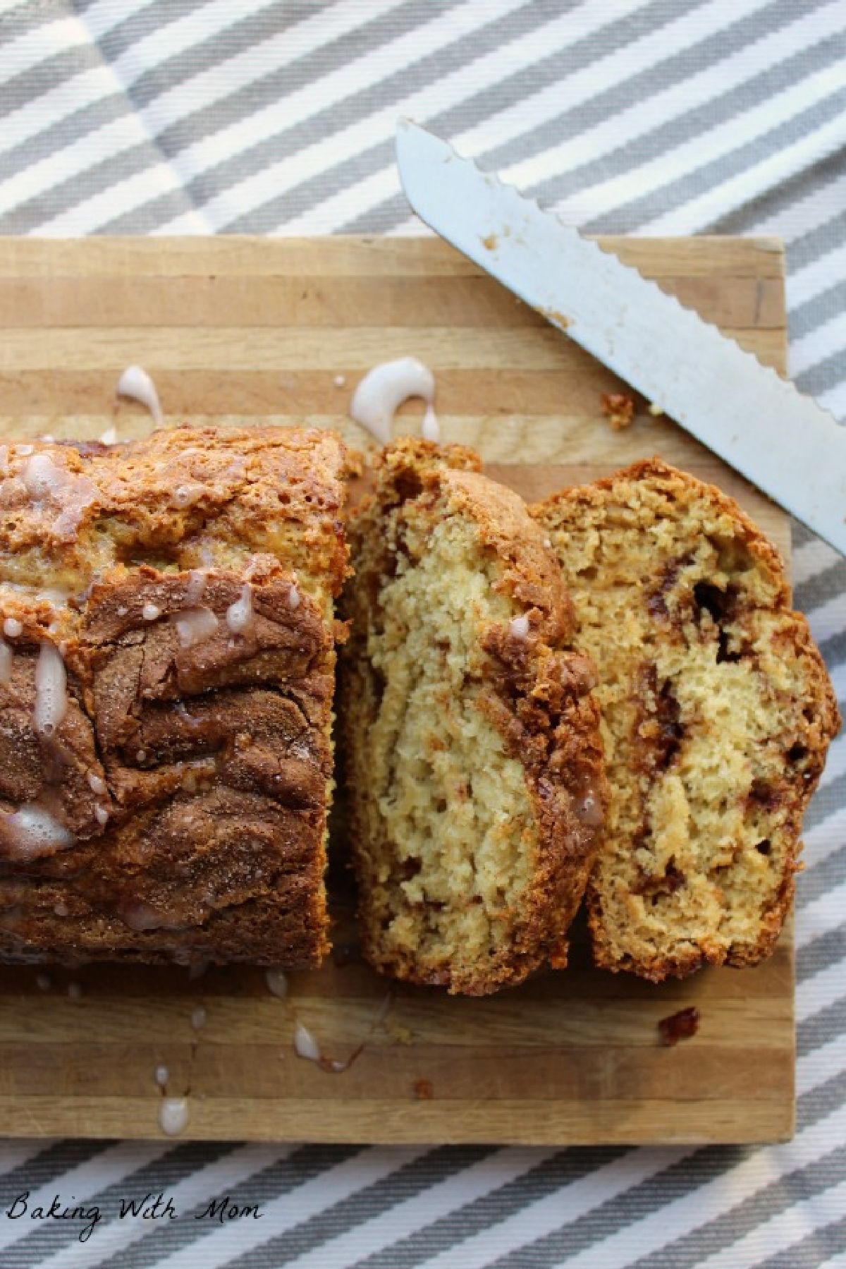 Cinnamon swirl bread on a cutting board with a bread knife laying besides.