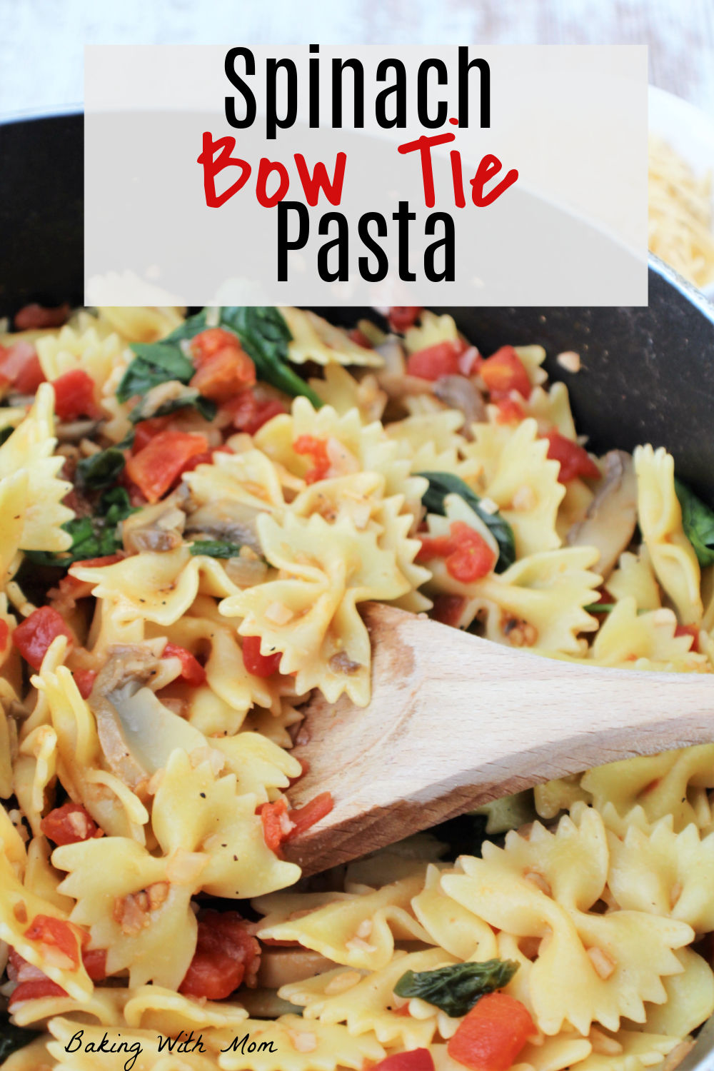 wooden spoon holding pasta and tomatoes with mushrooms and spinach. 