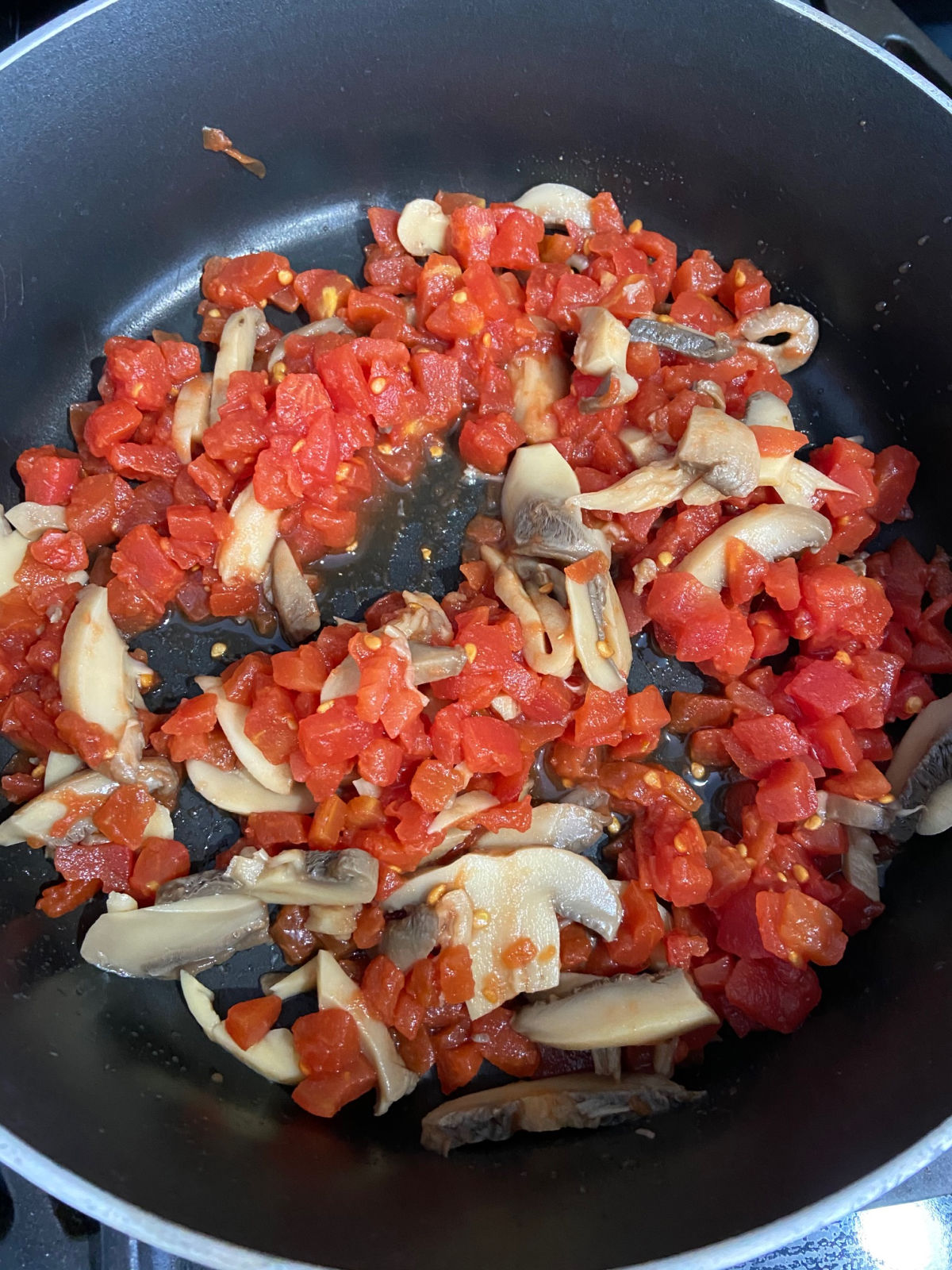 mushrooms and tomatoes cooking in a frying pan