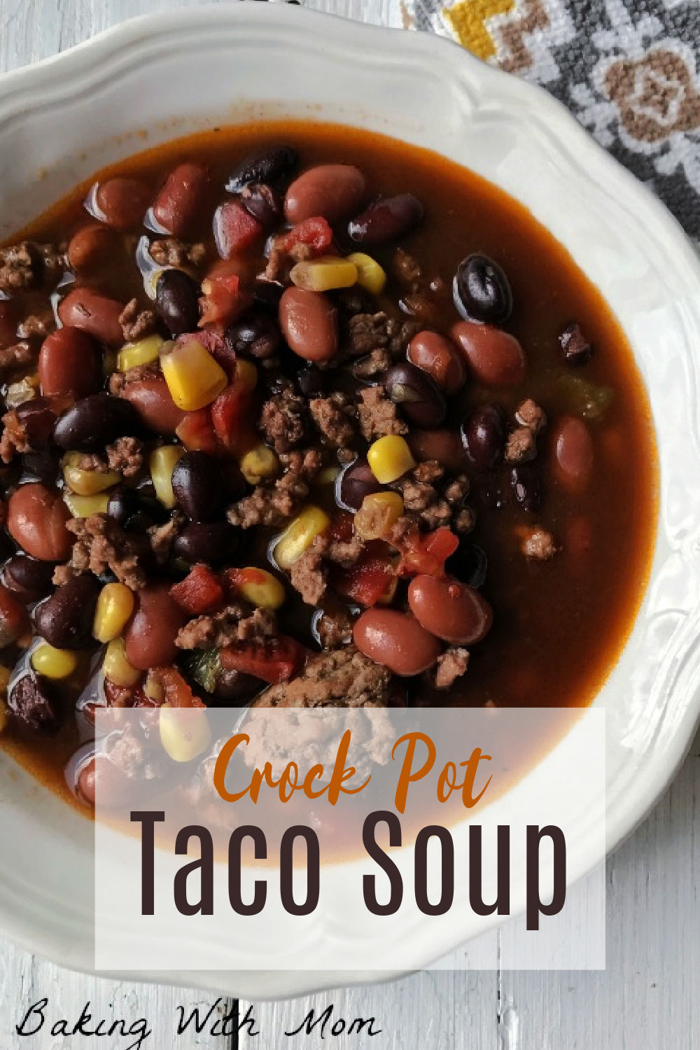 Beans, corns, ground beef in a white bowl with a yellow towel next to the bowl.