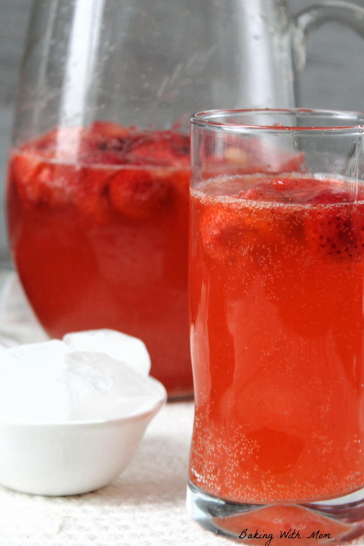 strawberry lime punch in a glass and pitcher.