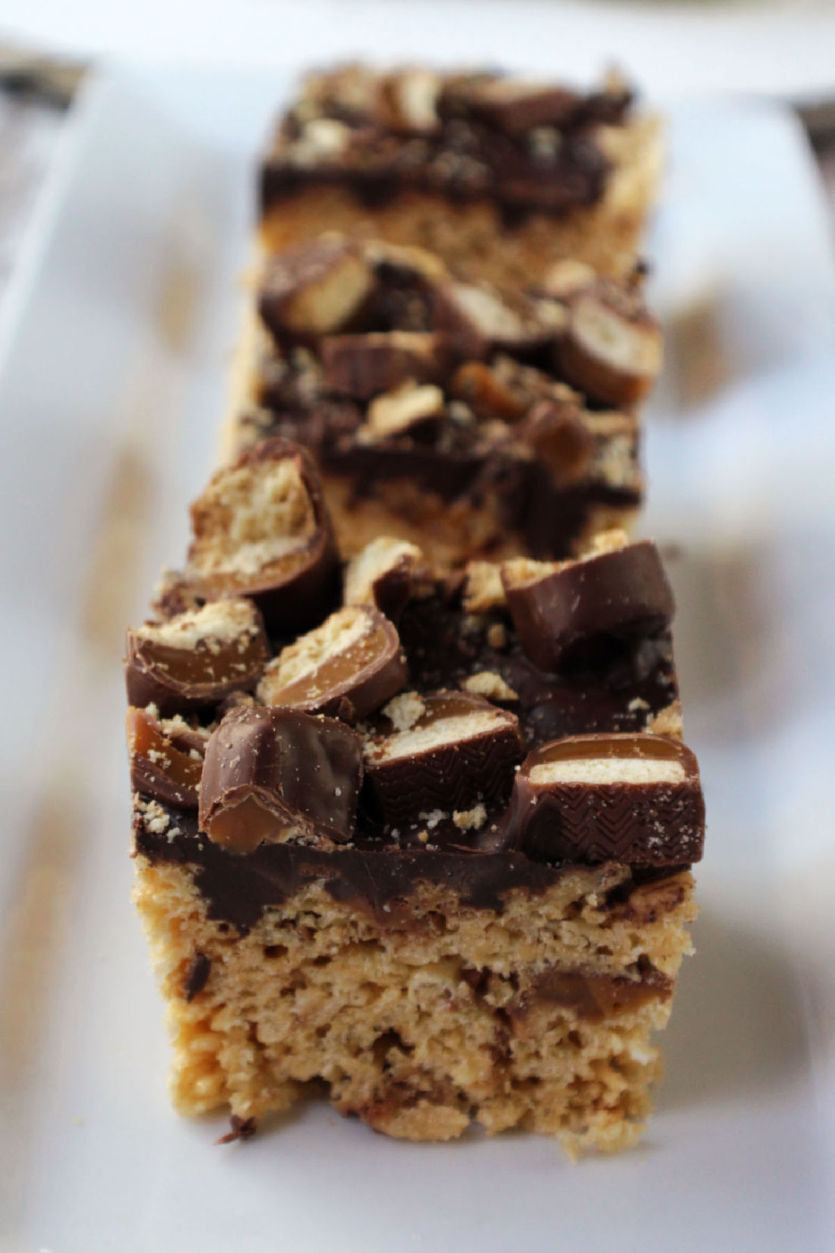 Plate of twix rice krispie treats with chocolate and caramel. 