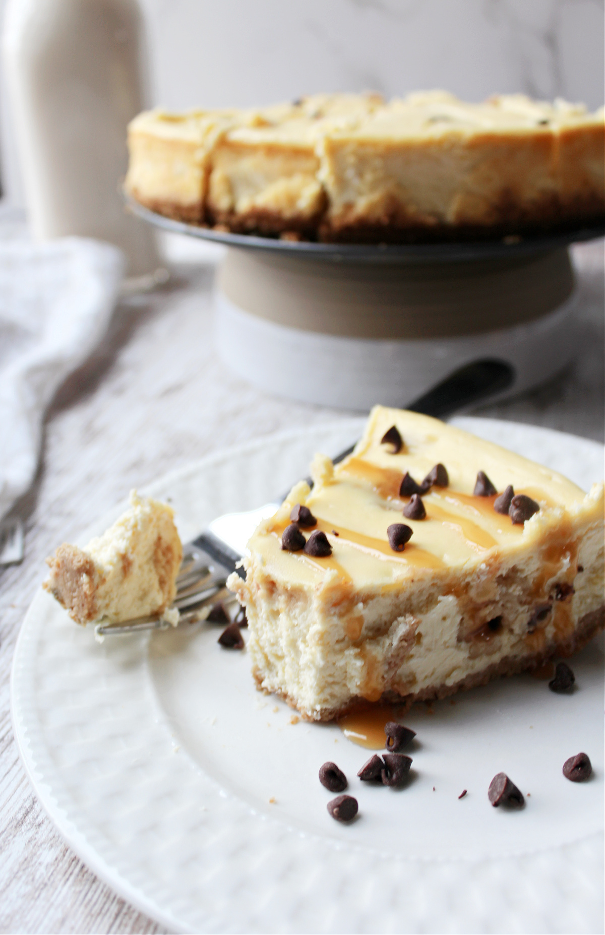 cookie dough cheesecake on a white plate with milk behind.