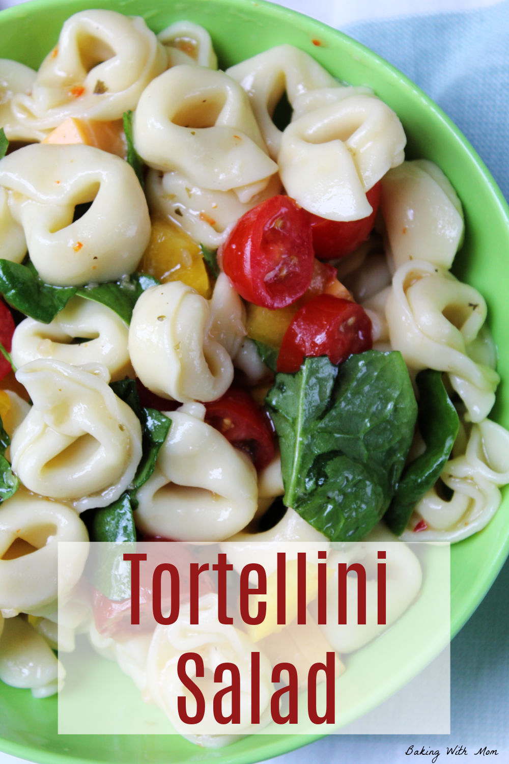 Bowl of tortellini, spinach, tomatoes in a green bowl. 