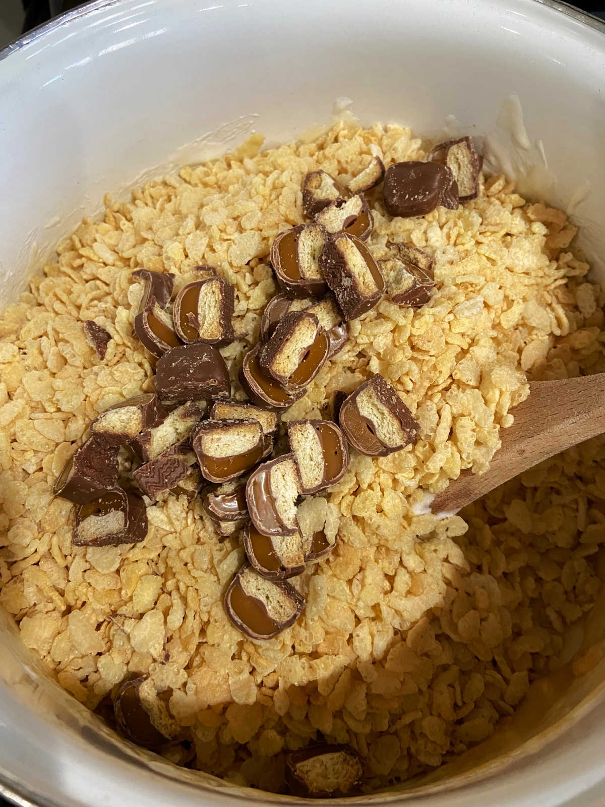 Adding the chopped Twix bars to Rice Krispie cereal.