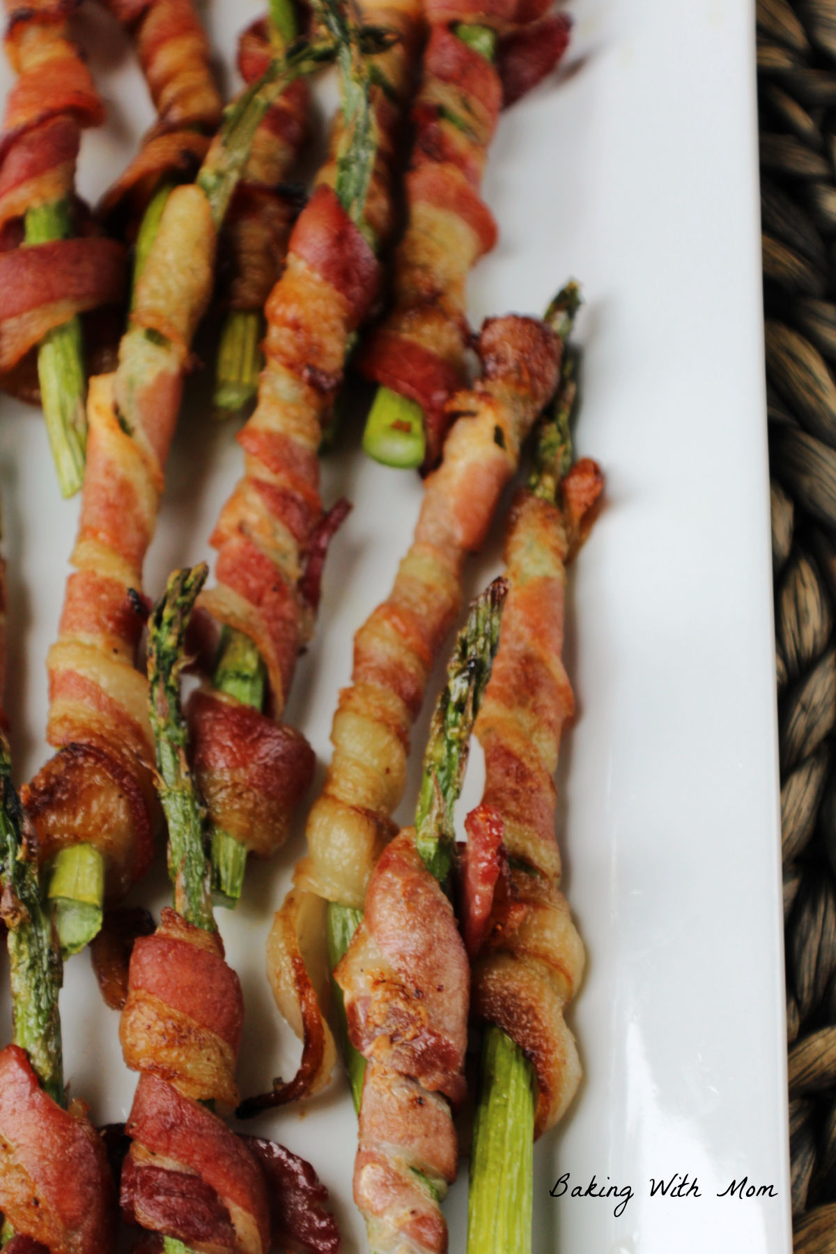 Asparagus wrapped in bacon on a white plate. 