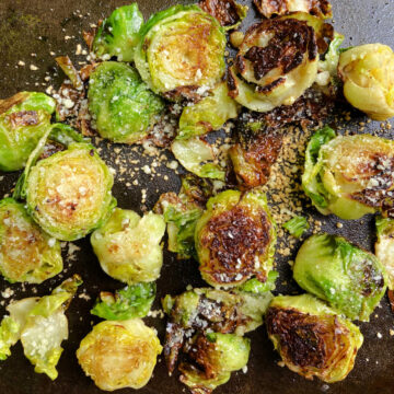 Brussel sprouts cooking on a flat top grill with bacon.