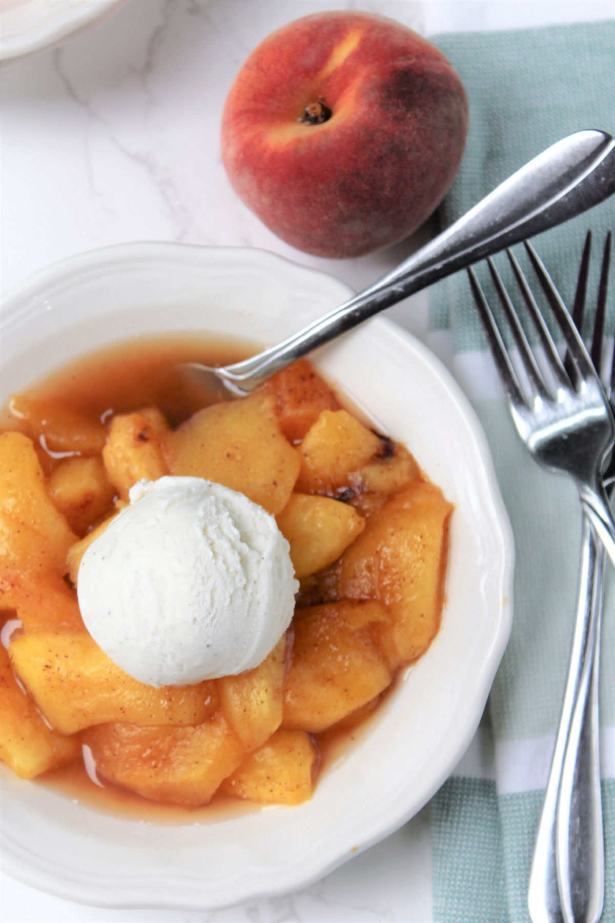 Ice cream on top of a bowl of peaches. 