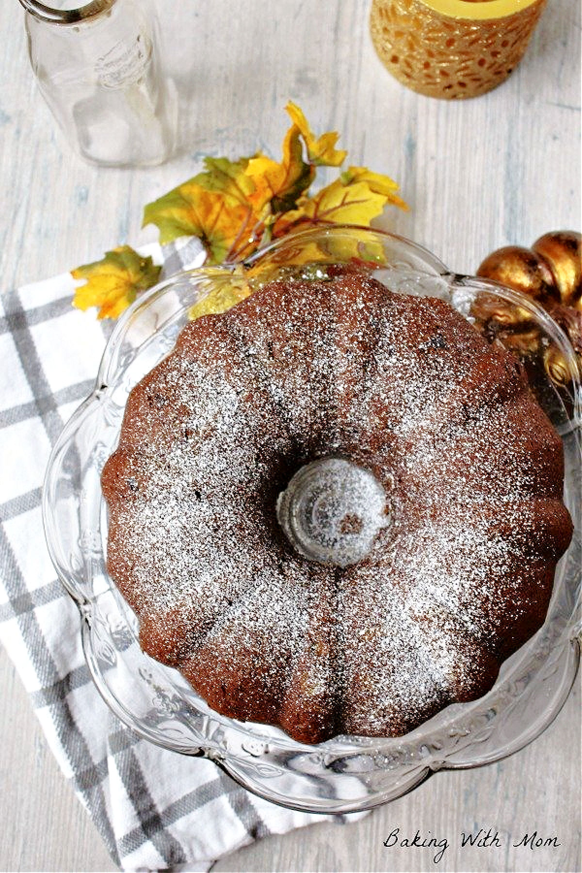Pumpkin chocolate chip cake with powdered sugar on top on a cake platter. 