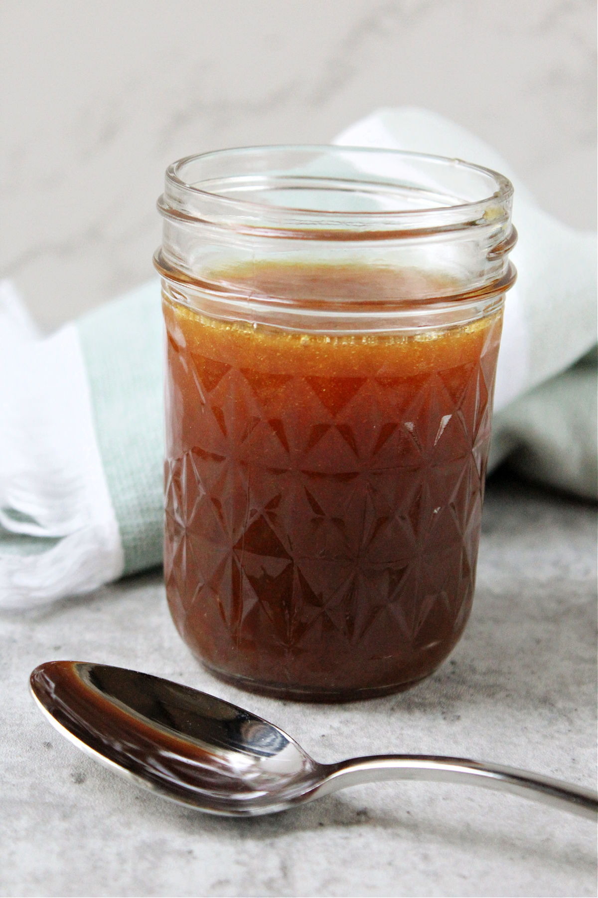 Caramel in a jar with a spoon lying nearby. 