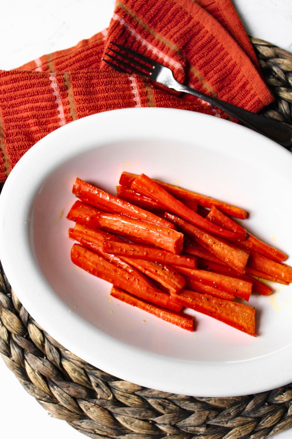 Roasted Brown Sugar Glazed Carrots in a white bowl with a fork nearby. 