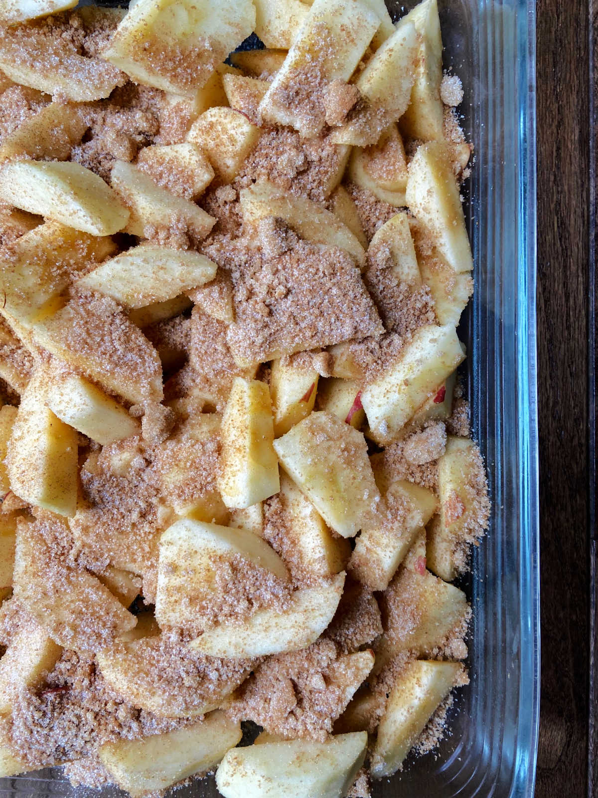 Raw apples in a pan with cinnamon mixture on top.