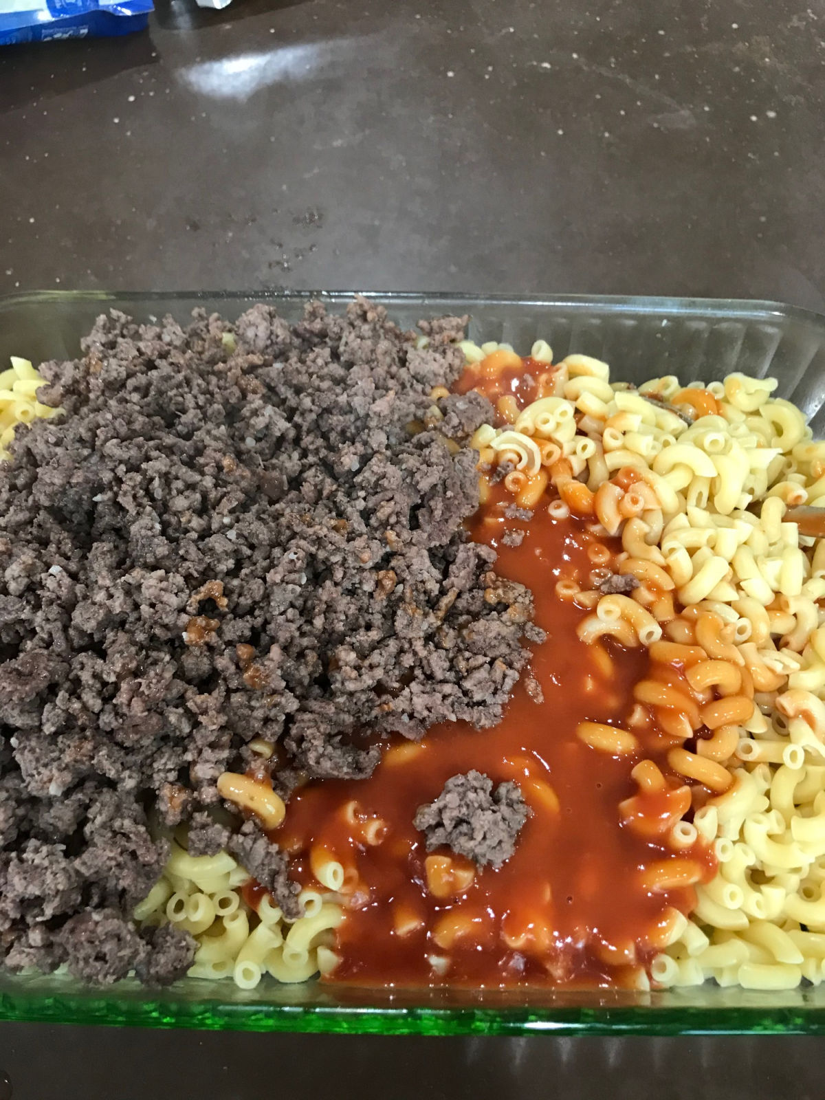 cooked noodles, hamburger and soup in a casserole dish.