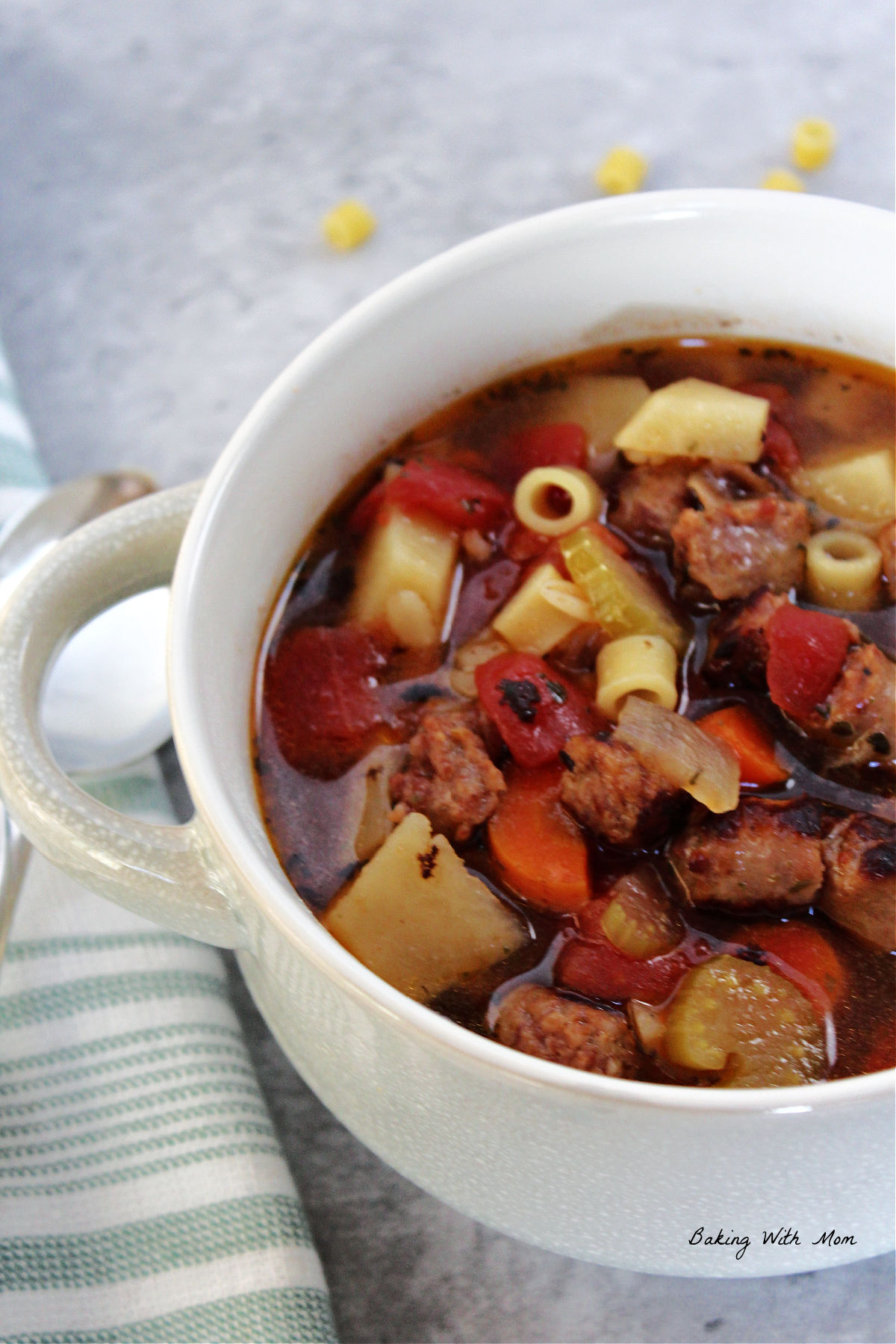 Easy Sausage Soup in a white bowl with a green towel laying besides. 