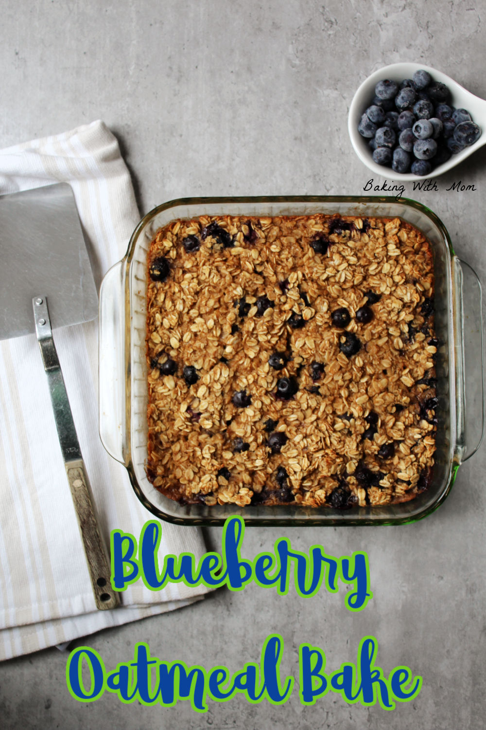 Blueberry oatmeal bake in a casserole dish with a spatula and towel laying besides. 