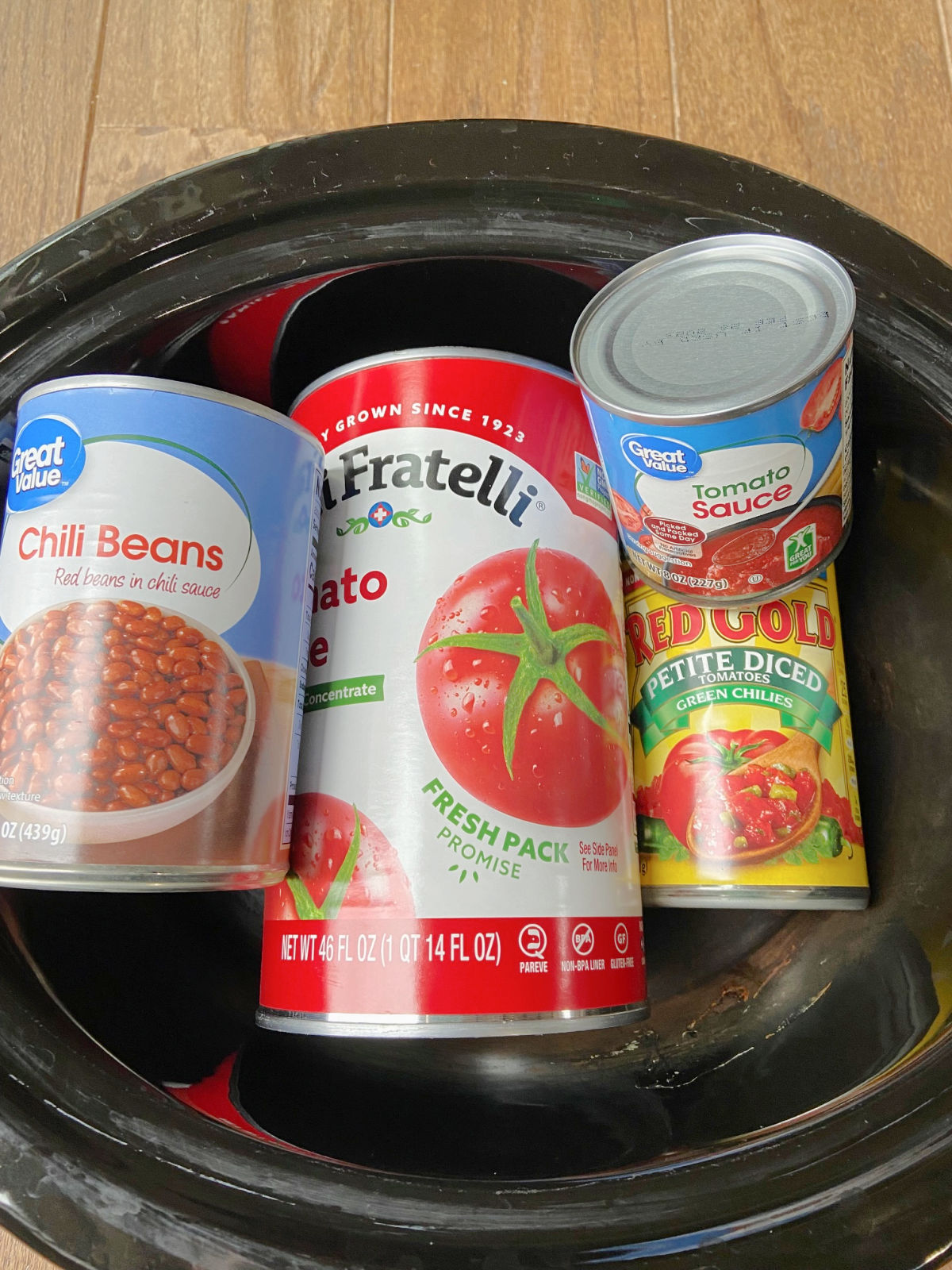 Cans of beans and sauce in a crock pot for chili.