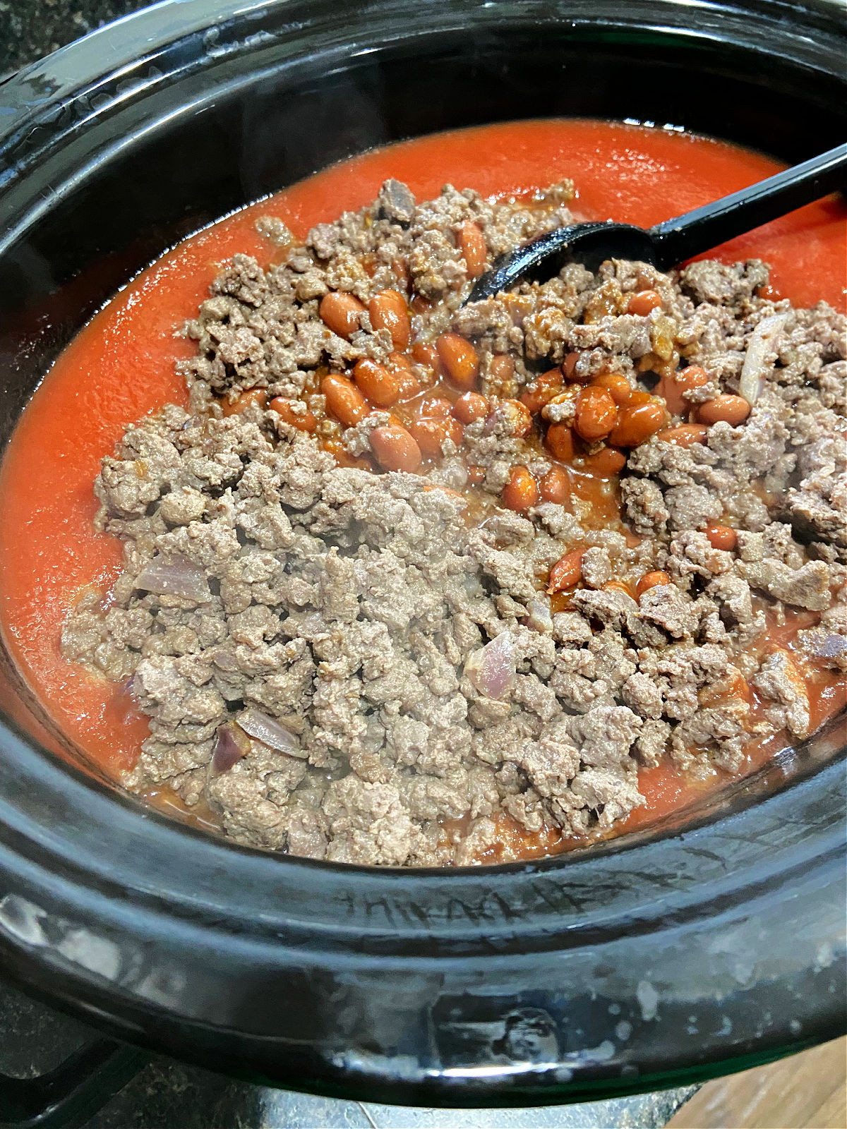 Venison stirred into a pot of chili.