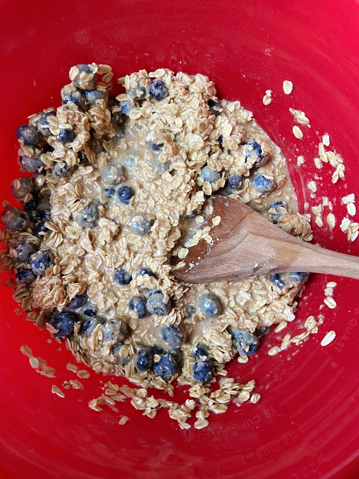 Uncooked oatmeal bake in a red bowl with blueberries. 