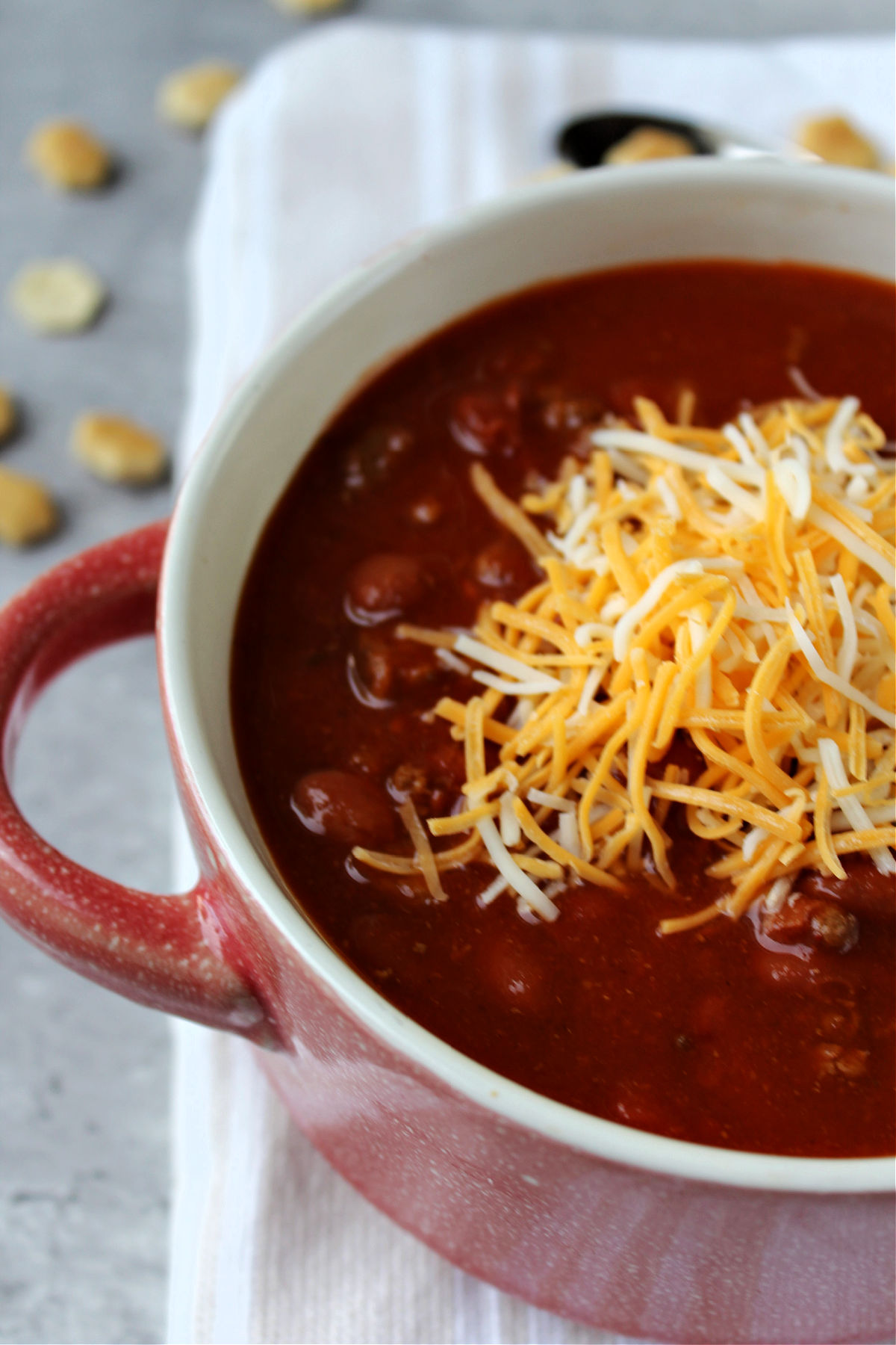 Chili in a red bowl with cheese on top. 