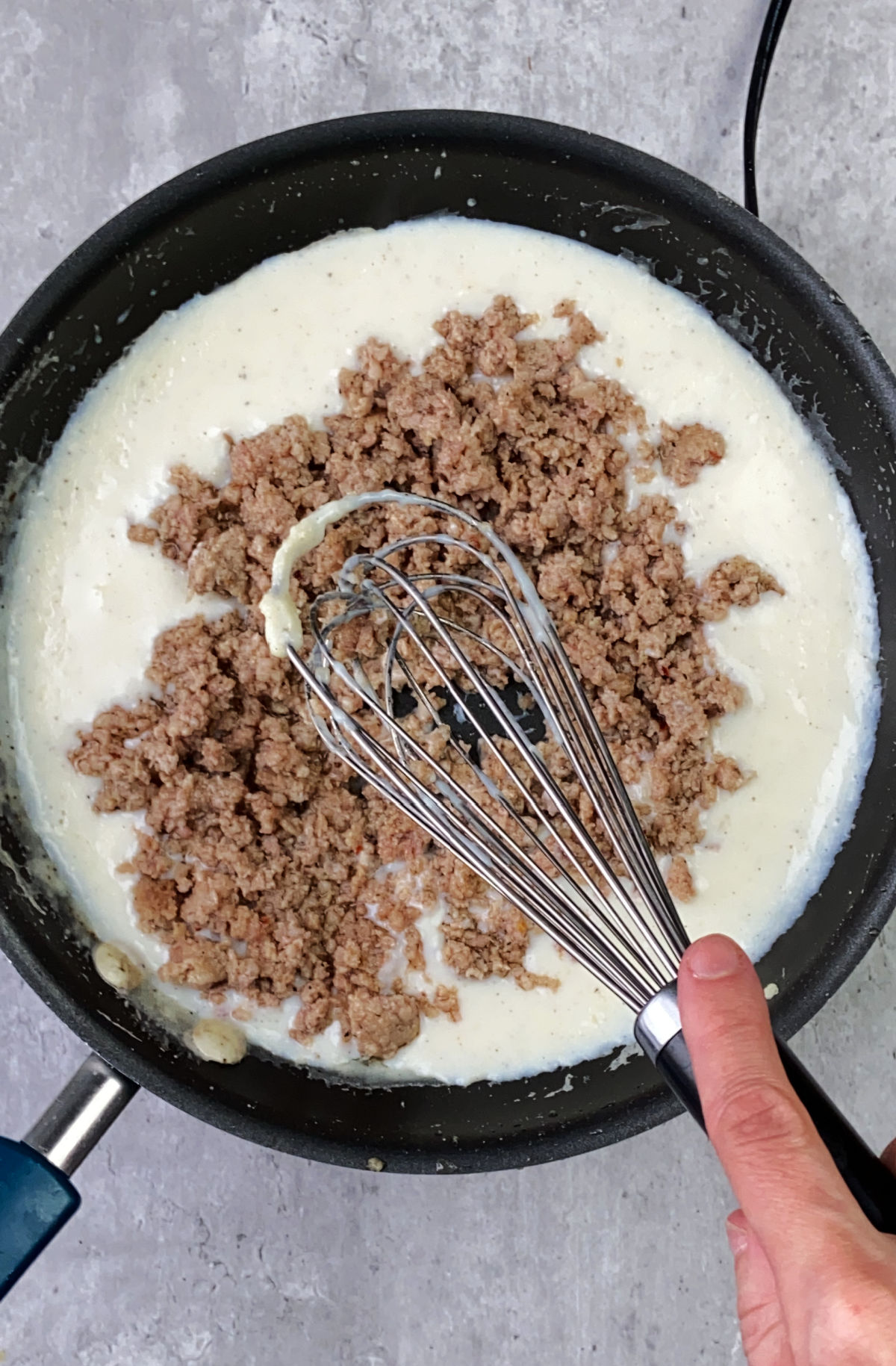 Sausage being mixed into a gravy mixture. 